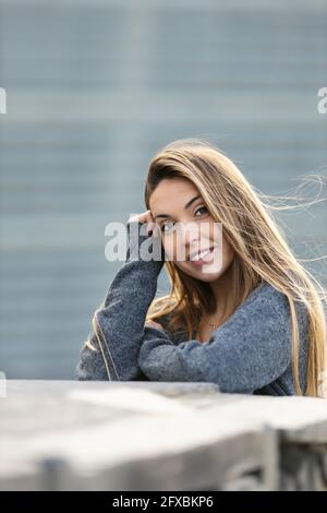 Junge Frau mit dem Kopf in den Händen, der sich an einer Stützwand lehnt Stockfoto