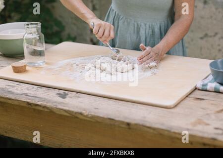 Reife Frau macht Teig auf Holztisch Stockfoto