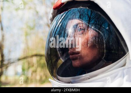 Weibliche Astronautin trägt Weltraumhelm wegschauen Stockfoto