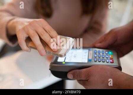 Frau, die im Restaurant über ein Smartphone bezahlt hat Stockfoto