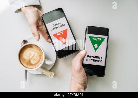 Frau, die die Zahlung an den Empfänger über ein Smartphone auf dem Tisch im Café macht Stockfoto