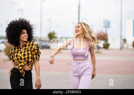 Glückliche Freundinnen, die draußen auf der Straße spazieren Stockfoto