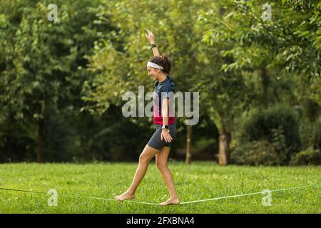 Weibliche Sportsperson Slacklining im Park Stockfoto