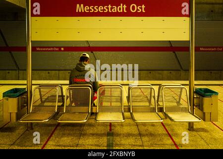 Ein Mann mit Baseballmütze sitzt auf einer Bank in der Münchner U-Bahnstation Messestadt Ost. Stockfoto