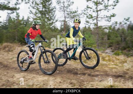 Brüder fahren Fahrrad auf unbefestigten Straße im Wald Stockfoto