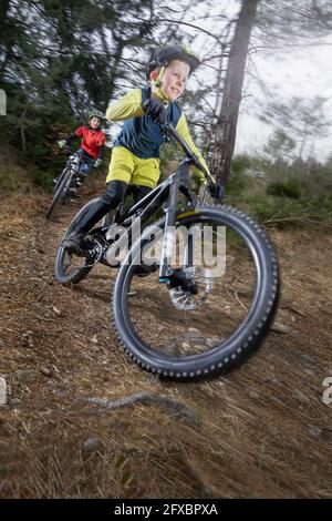 Geschwister fahren Fahrrad auf Feldweg im Wald Stockfoto