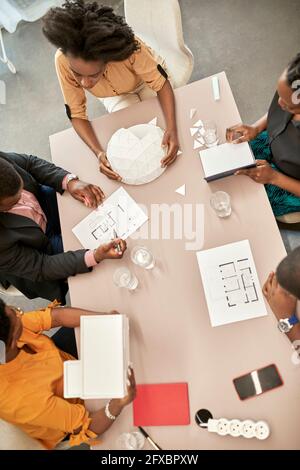 Männliche und weibliche Architekten diskutieren über Model während des Meetings am Schreibtisch im Coworking Office Stockfoto