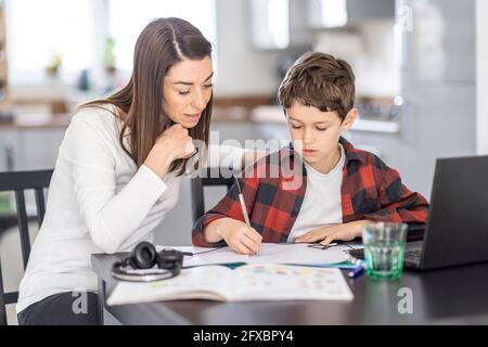 Frau, die dem Sohn hilft, zu Hause zu studieren Stockfoto