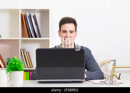 Mann lächelt mit dem Computer zu Hause oder im Büro Stockfoto