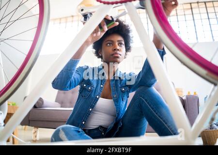 Afro-Frau hält Arbeitswerkzeug während der Reparatur Fahrrad zu Hause Stockfoto