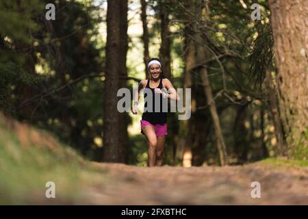 Junge Sportlerin, die im Wald läuft Stockfoto