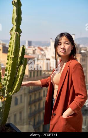 Frau, die mit Händen in Taschen auf der Dachterrasse steht Stockfoto