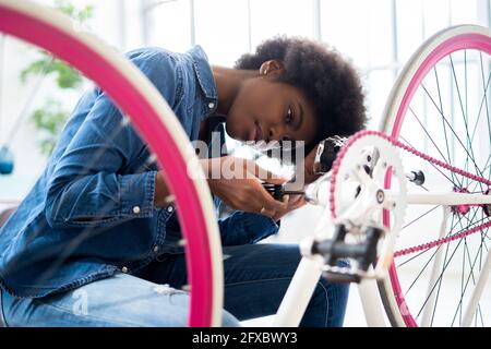 Junge Frau in Casuals Reparatur Fahrrad zu Hause Stockfoto