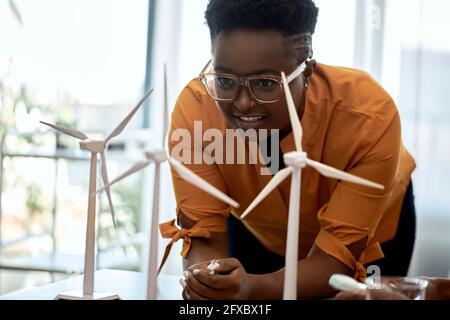 Frau mit Brille, die im Büro Modelle von Windenergieanlagen untersucht Stockfoto