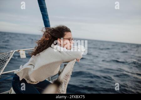 Frau, die sich im Urlaub auf dem Segelboot auf dem Netz lehnte Stockfoto