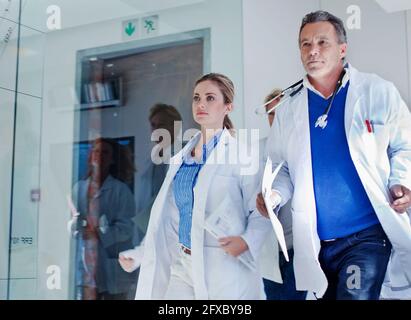 Weibliche und männliche Ärzte, die während der Notdurst im Krankenhaus im Korridor laufen Stockfoto