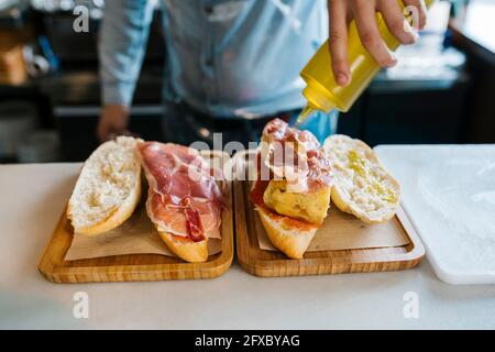 Küchenchef gießt Olivenöl auf Sandwiches in einem Restaurant Stockfoto