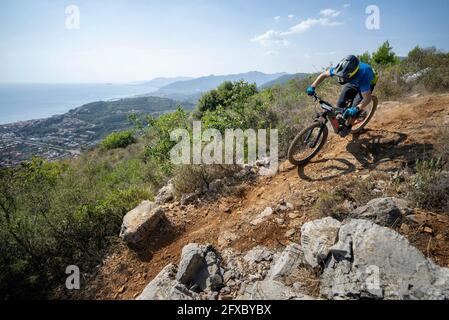 Mann, der an sonnigen Tagen auf dem Berg mit dem Elektrofahrrad fährt Stockfoto