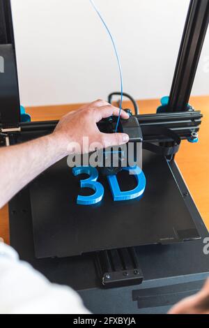 Junger männlicher Techniker, der 3D-Drucker verwendet Stockfoto