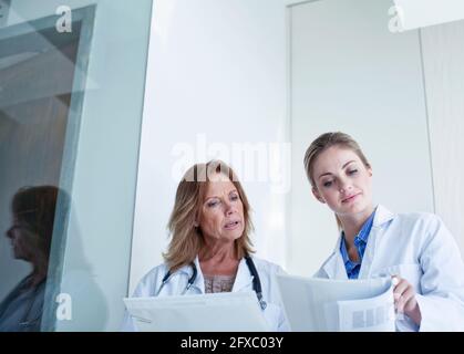 Ärztinnen, die Dokumente betrachten, während sie im Krankenhaus diskutieren Stockfoto