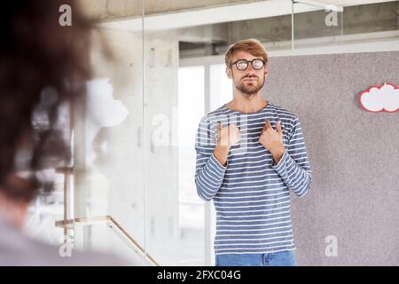 Ein hübscher Mann, der eine Brille trägt und vor der Trennwand steht Stockfoto
