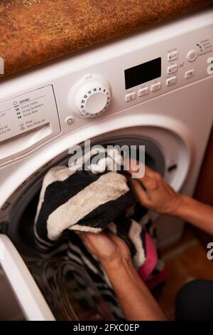 Reife Frau, die zu Hause Kleidung in die Waschmaschine lädt Stockfoto