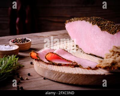 Rosmarinschinken auf Holzbrett mit Salz und Pfeffer in Schüsseln, Brot und Rosmarin Stockfoto