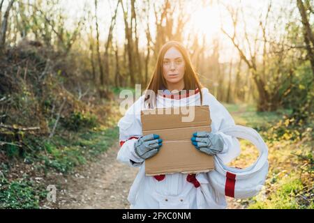 Junge Astronautin mit Pappe im Wald Stockfoto