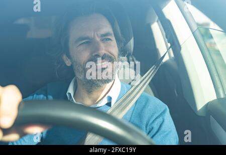 Reifer männlicher Unternehmer lächelt beim Autofahren Stockfoto