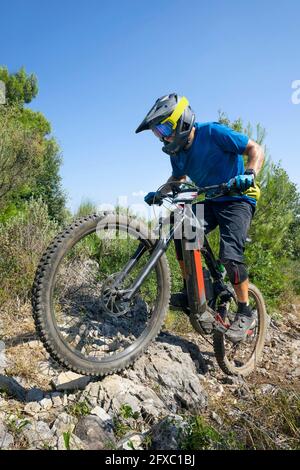 Männlicher Radfahrer, der an sonnigen Tagen auf Felsen mit Elektrofahrrad fährt Stockfoto