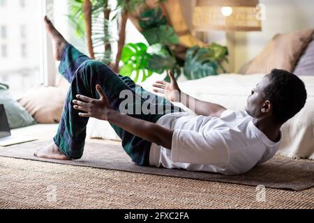 Mann, der im Haus Yoga praktiziert, indem er Boot Pose oder Paripurna Navasana macht Stockfoto