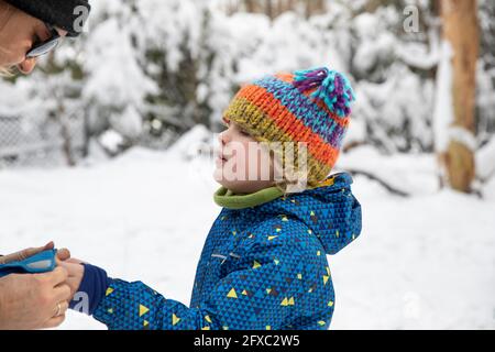 Mutter hilft dem Sohn im Winter mit Handschuhen Stockfoto