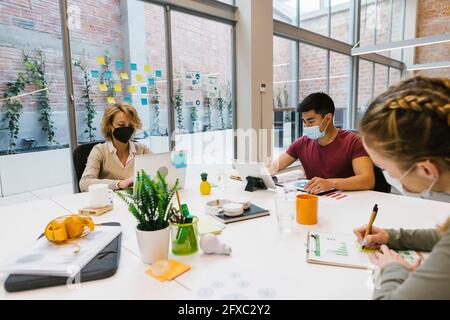 Während der COVID-19 arbeiteten männliche und weibliche Fachkräfte am heißen Schreibtisch Stockfoto
