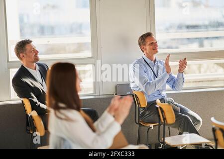 Männliche und weibliche Unternehmer klatschen, während sie im Konferenzzentrum sitzen Stockfoto