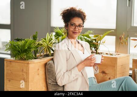Selbstbewusste Geschäftsfrau mit Kaffeetasse im Büro Stockfoto