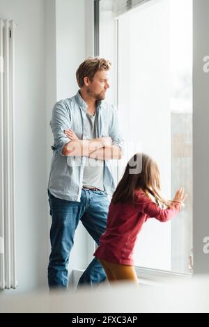 Vater und Tochter stehen durch die Fenster zu Hause Stockfoto