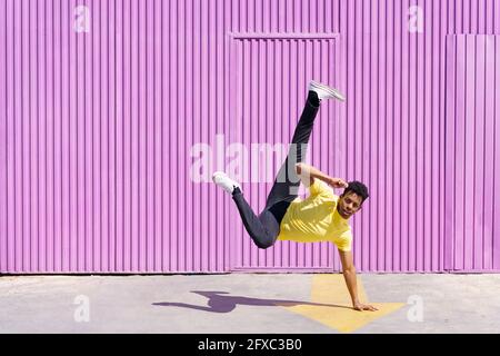 Mann, der an sonnigen Tagen auf dem Fußweg Handstand macht Stockfoto