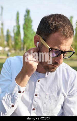 Geschäftsmann passt an sonnigen Tagen kabellose Kopfhörer an Stockfoto