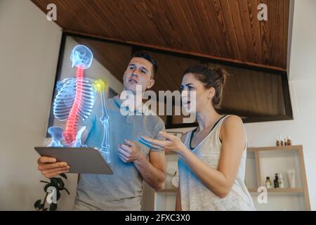 Physiotherapeutin, die bei einer Patientin die Ursache von Schmerzen im Schultergelenk zeigt Stockfoto