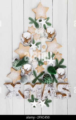 Anordnung von hausgemachten Keksen und verschiedenen Weihnachtsdekorationen, die an der Holzwand hängen Stockfoto