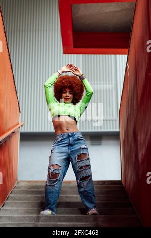 Afro-Frau mit erhobenen Armen auf der Treppe stehend Stockfoto