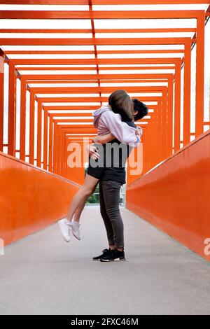 Teenager Junge Abholung Freundin auf orange Brücke Stockfoto