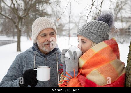 Mann, der im Winter die Frau beim Teetrinken im Becher ansieht Stockfoto