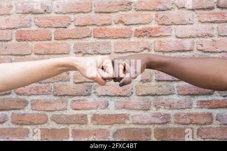 Freundinnen geben Fauststoß durch Ziegelwand Stockfoto