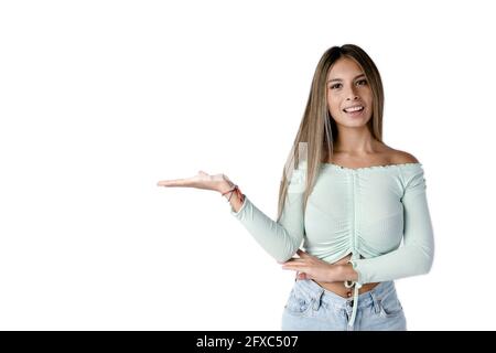 Schöne lateinische Frau, die mit ausgestreckten rechten Arm und geöffneter Hand auf einem rein weißen Hintergrund nach vorne blickt. Stockfoto