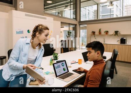 Geschäftsfrau diskutiert Strategie mit männlichem Kollegen im Coworking Büro Stockfoto
