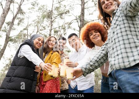 Lächelnder junger Mann, der während einer Party im Wald Selfie beim Gläsern toasten nimmt Stockfoto