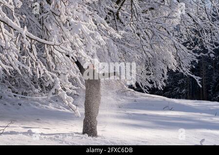 Junge Frau genießt den Winter unter schneebedecktem Baum Stockfoto