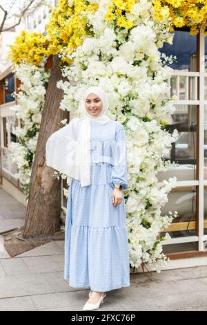 Lächelnde Frau mit Hijab, die auf dem Fußweg steht Stockfoto