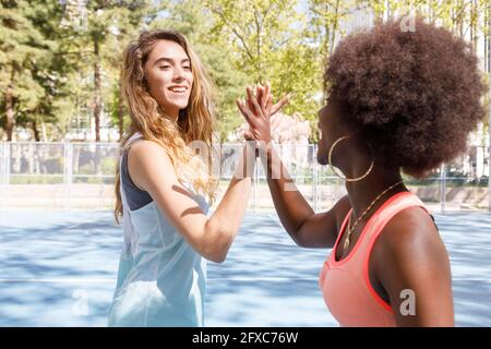 Junge Frauen geben High-Five, während sie auf dem Sportplatz stehen Stockfoto